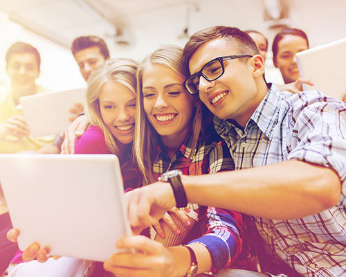Mehrere Jugendliche informieren sich lächelnd gemeinsam an einem Laptop.